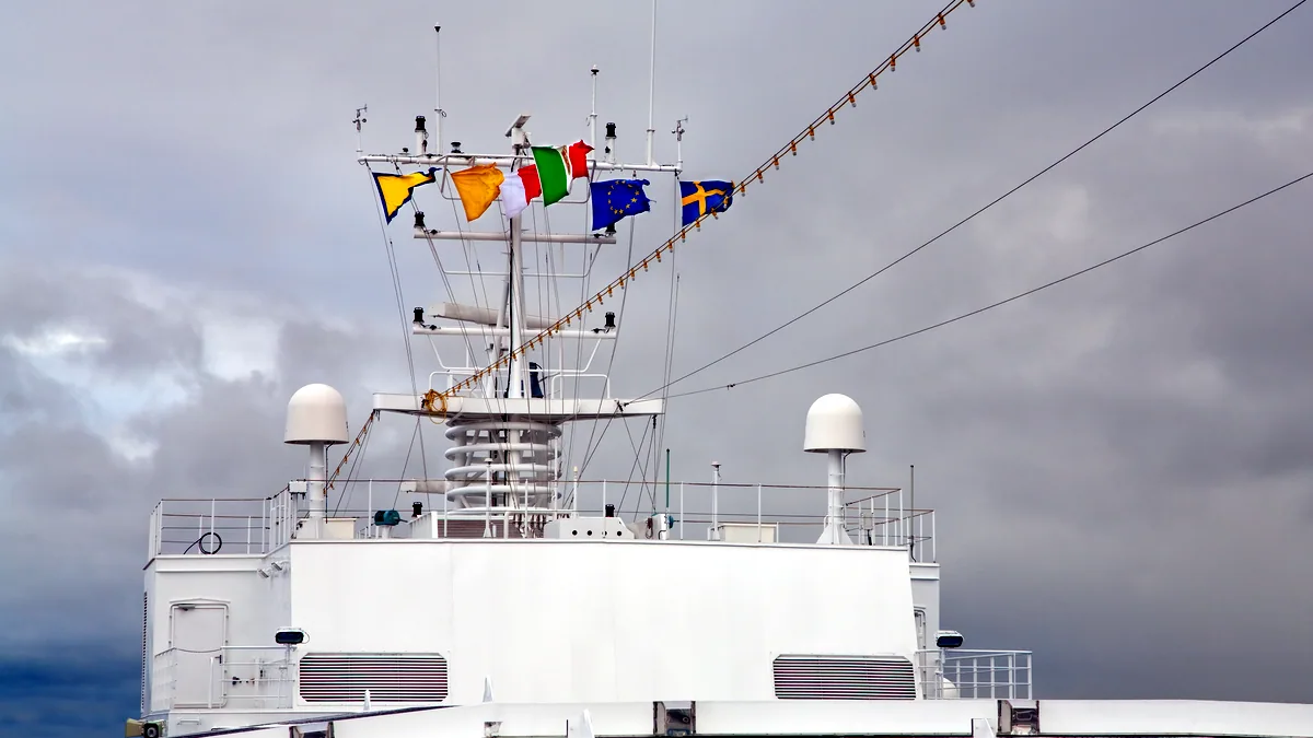 A line of naval flags strung along ship rigging, their fabric rippling in the harbour wind.