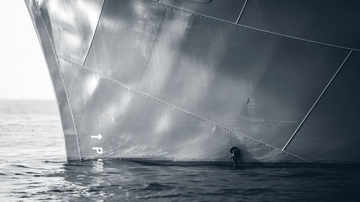 Illustration: A close view of a weathered grey warship bow, blank steel plating meeting grey water in soft light.